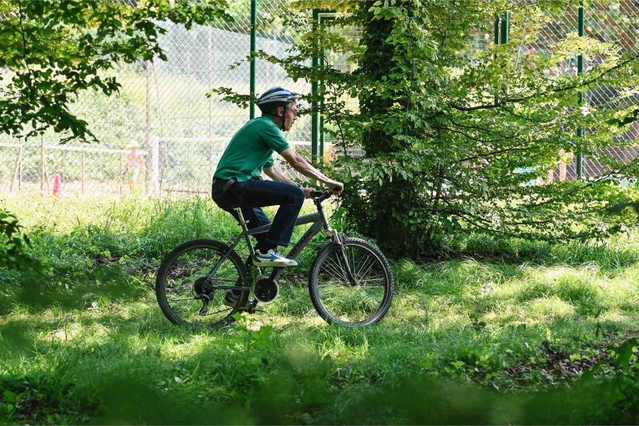 Un groupe de cyclistes tout-terrain parcourant un sentier forestier ensoleillé dans la forêt de Meudon, entouré d'arbres verdoyants.​